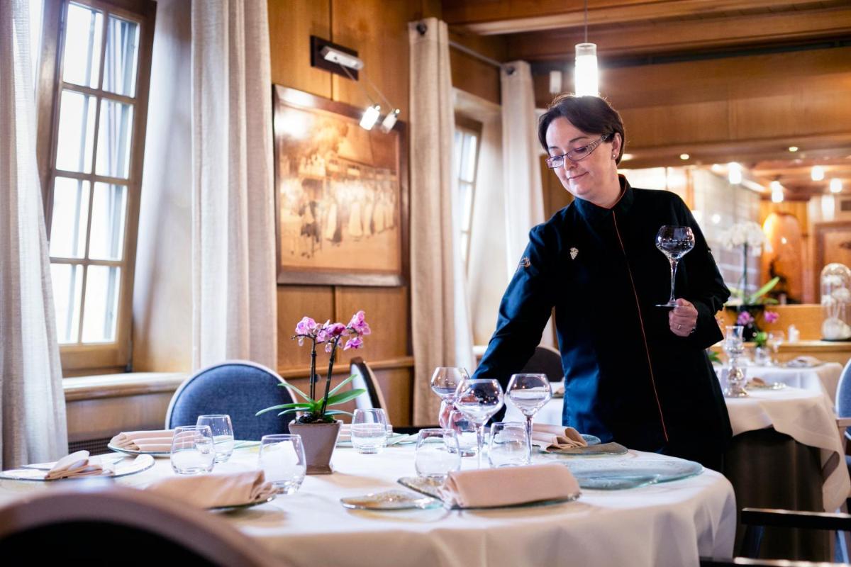 une femme debout devant une table avec des verres à vin dans l'établissement Hotel - Restaurant Le Cerf & Spa, à Marlenheim