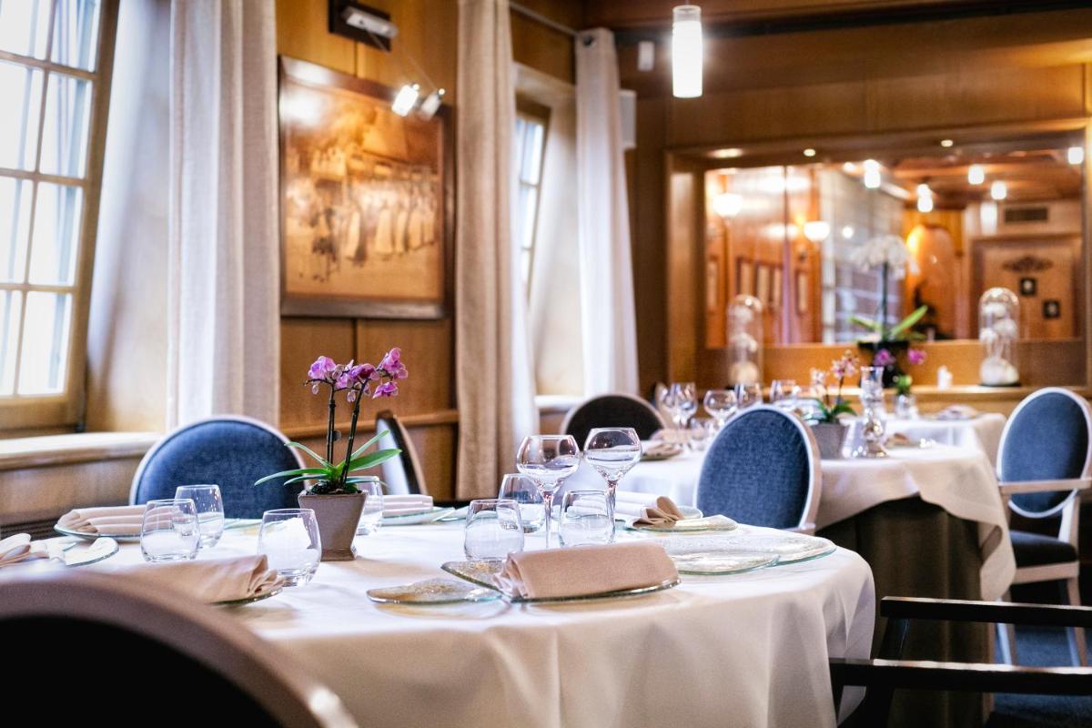 une salle à manger avec des tables et des chaises recouvertes de nappes blanches dans l'établissement Hotel - Restaurant Le Cerf & Spa, à Marlenheim
