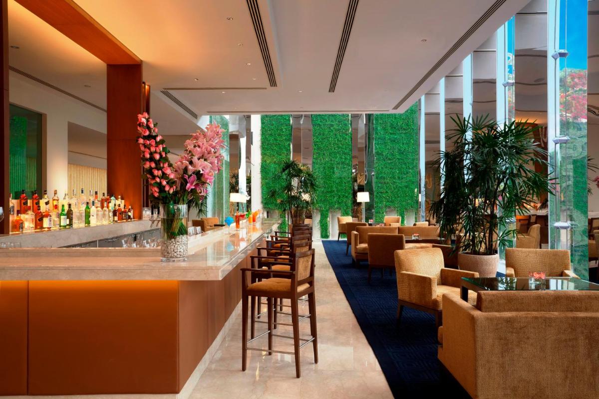a restaurant with a bar with chairs and plants at The Oberoi Gurgaon in Gurgaon a restaurant with a bar with chairs and plants at The Oberoi Gurgaon in Gurgaon