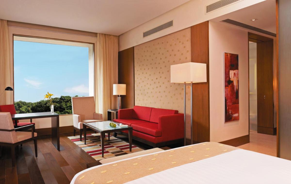 a hotel room with a red couch and a desk at The Oberoi Gurgaon in Gurgaon