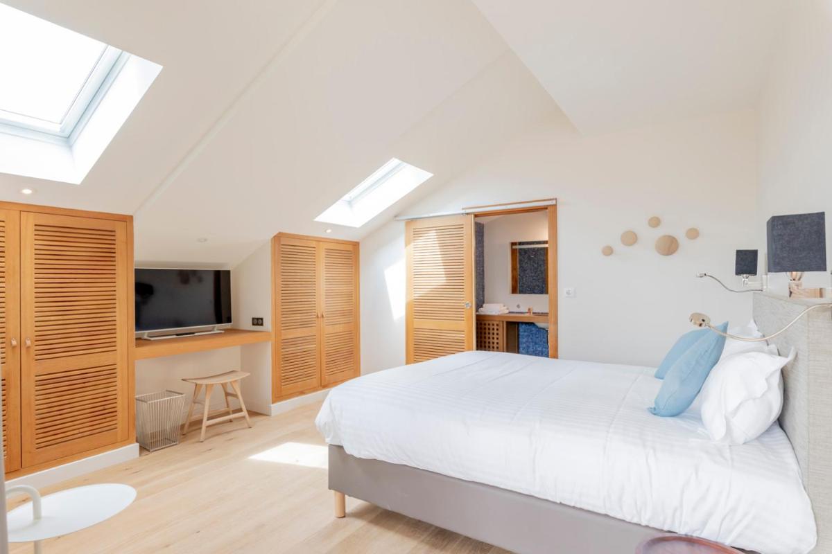 une chambre blanche avec un lit et une télévision dans l'établissement Résidence Les Suites du Port - by Le Saint Ferdinand, à Arcachon
