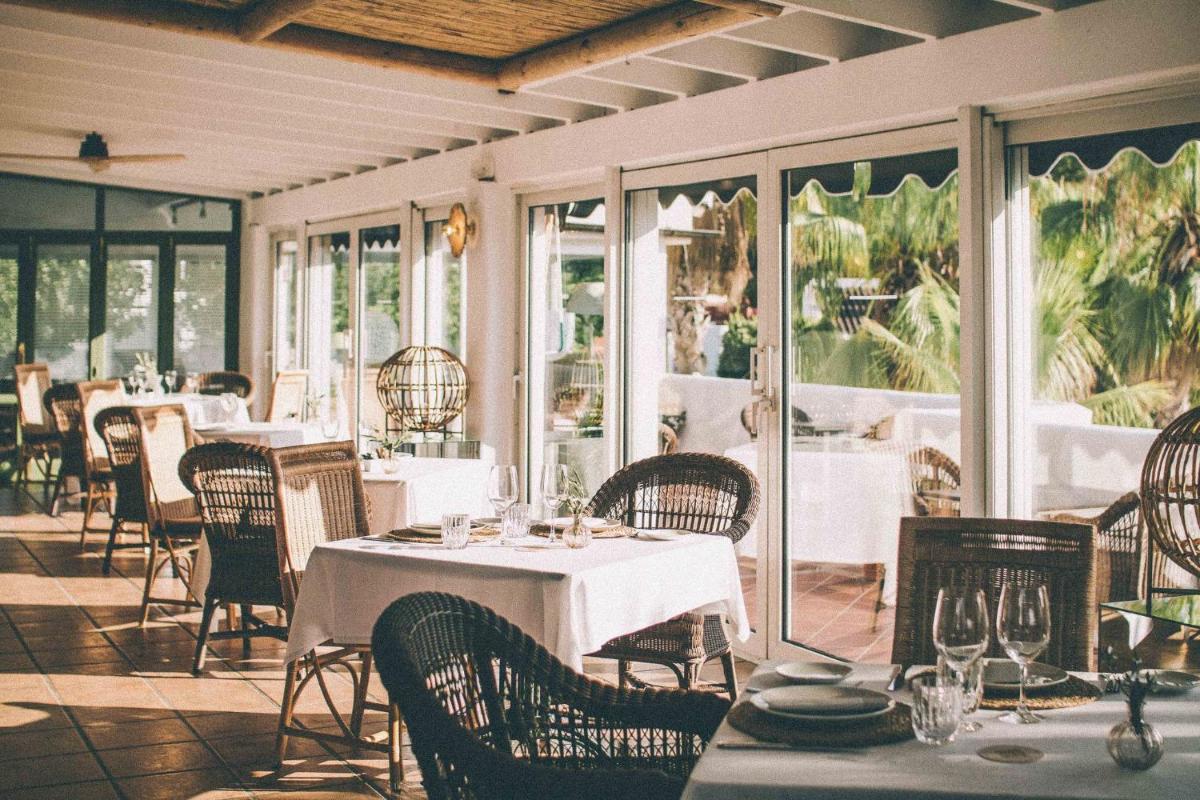Un comedor con mesas y sillas y ventanas. en Hotel Ritual de Terra & SPA, en Jávea