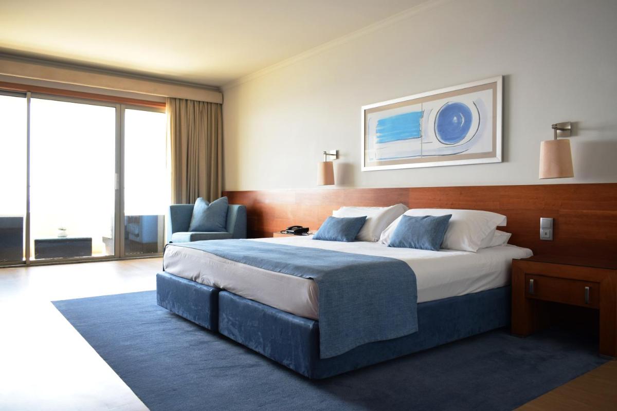 um quarto de hotel com uma cama grande e uma janela em Madeira Regency Cliff - Adults Only no Funchal