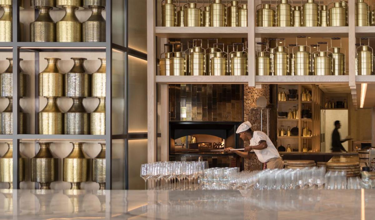 a man in a kitchen preparing food in a room with jars at Four Seasons Hotel Bengaluru at Embassy ONE in Bengaluru a man in a kitchen preparing food in a room with jars at Four Seasons Hotel Bengaluru at Embassy ONE in Bengaluru