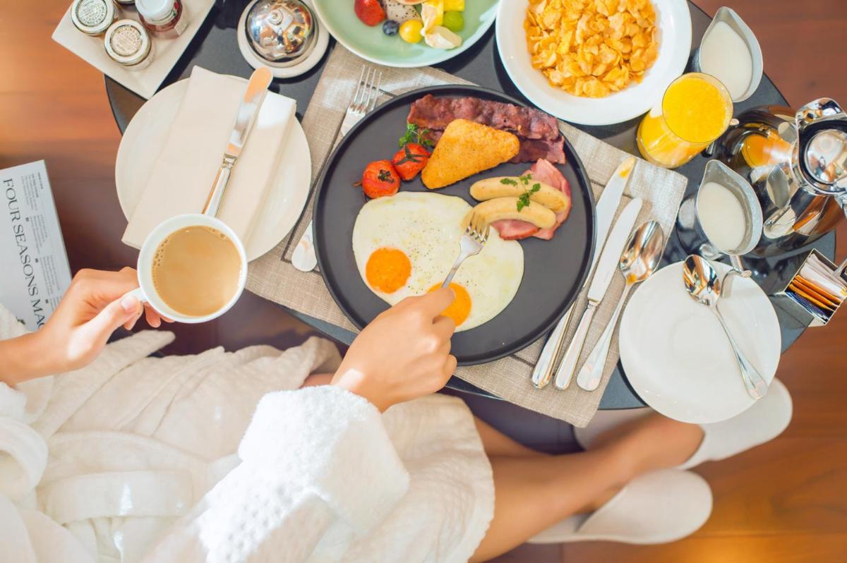 a person sitting at a table with a plate of breakfast food at Four Seasons Hotel Bengaluru at Embassy ONE in Bengaluru a person sitting at a table with a plate of breakfast food at Four Seasons Hotel Bengaluru at Embassy ONE in Bengaluru