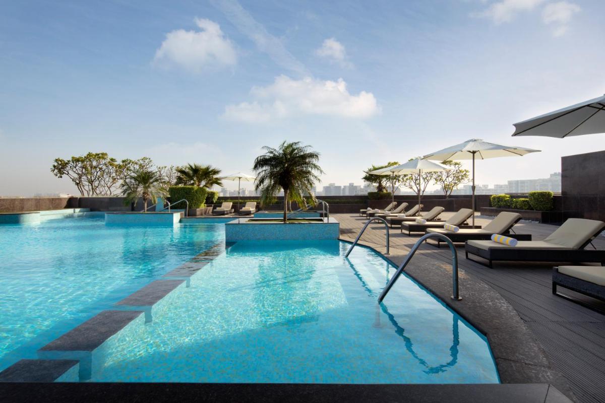 a pool at a hotel with lounge chairs and umbrellas at Radisson Blu Hotel New Delhi Dwarka in New Delhi a pool at a hotel with lounge chairs and umbrellas at Radisson Blu Hotel New Delhi Dwarka in New Delhi