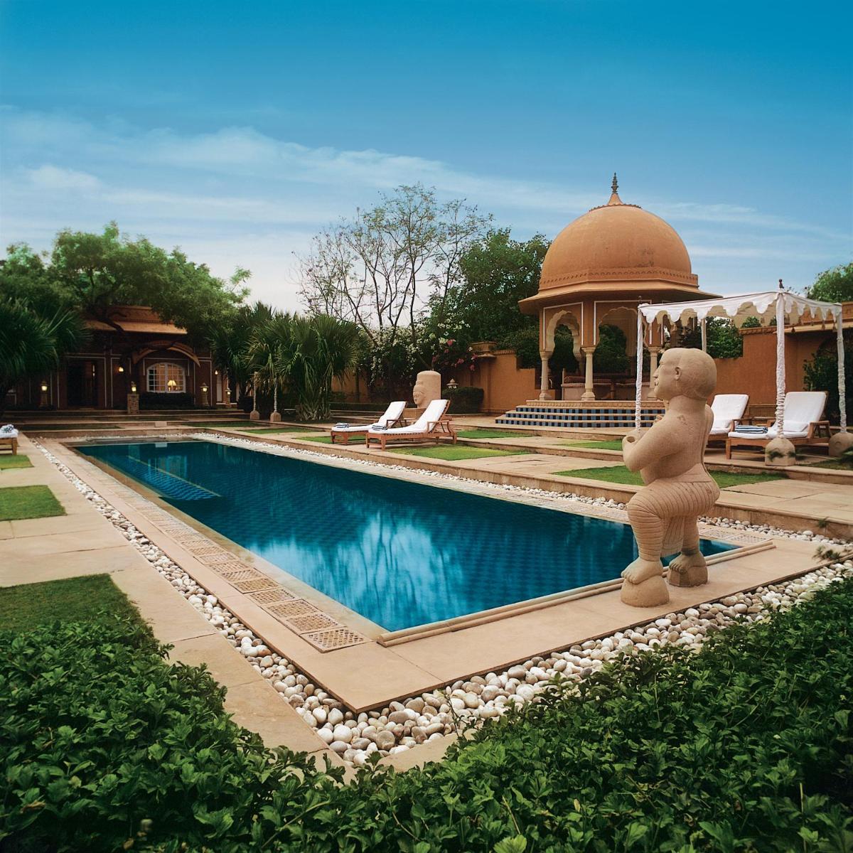 a teddy bear statue standing next to a swimming pool at The Oberoi Rajvilas Jaipur in Jaipur
