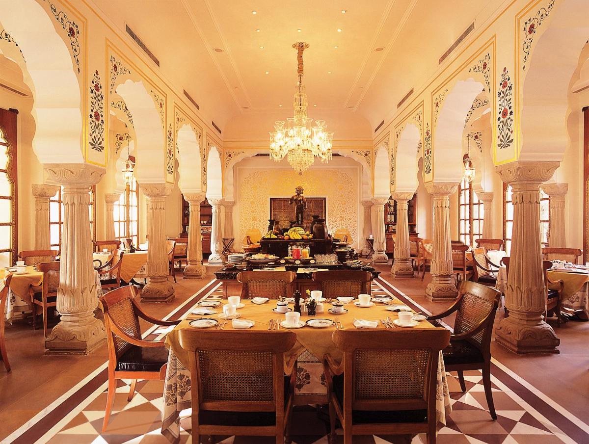 a dining room with a table and chairs and a chandelier at The Oberoi Rajvilas Jaipur in Jaipur