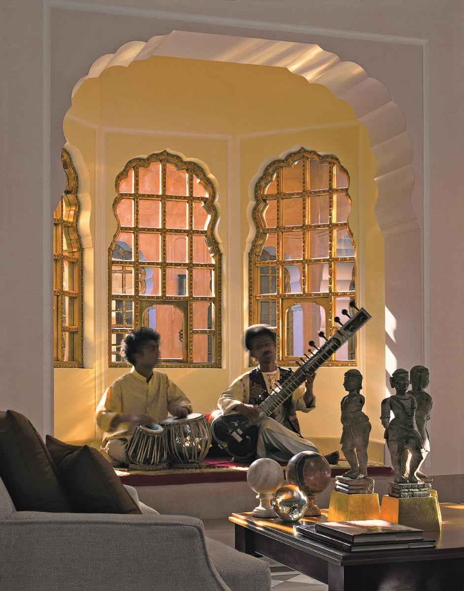 two people sitting in a living room with a guitar at The Oberoi Rajvilas Jaipur in Jaipur