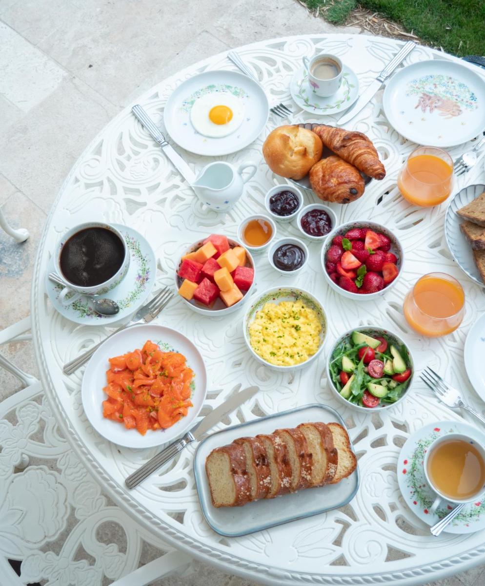 une table blanche recouverte de assiettes de nourriture et d'œufs dans l'établissement Hôtel Maison Pavlov - Restaurant & Spa - Bordeaux Bouscat, à Le Bouscat