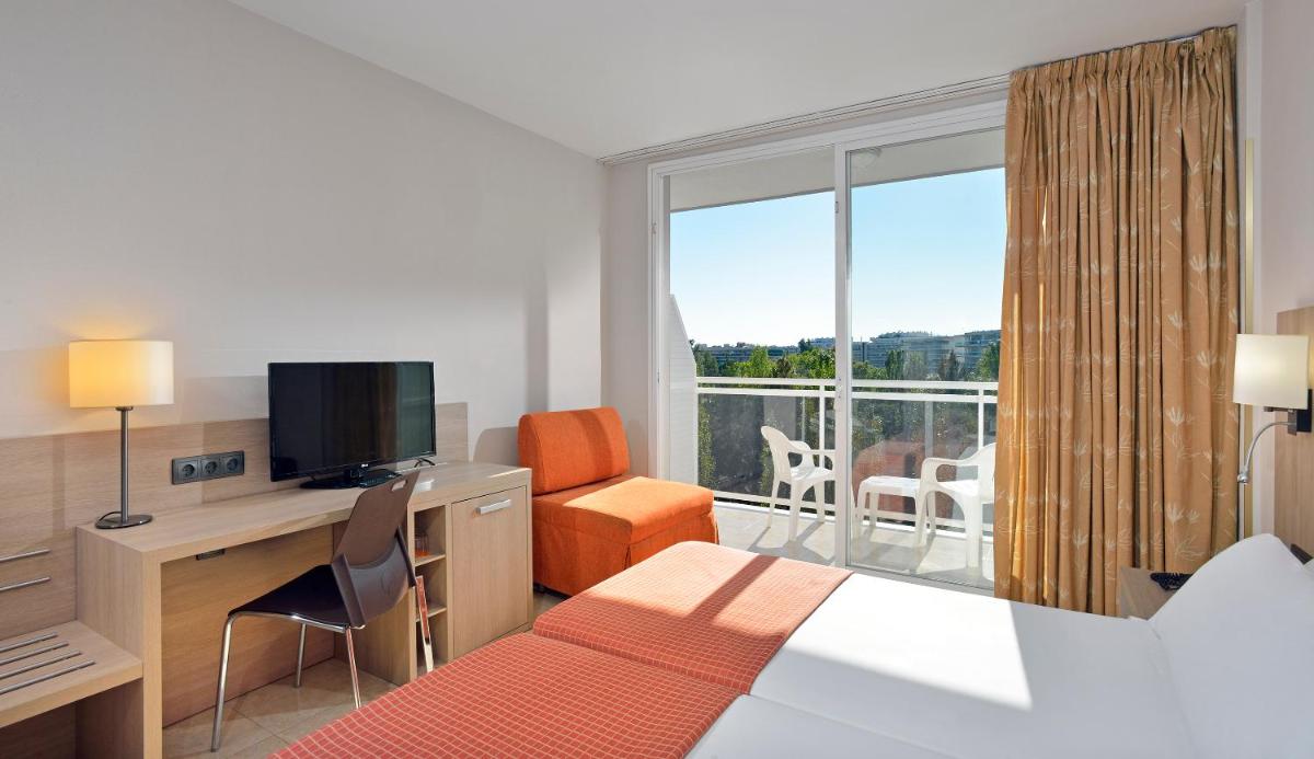 Una habitación de hotel con una cama y un escritorio con televisión. en Sol Costa Daurada, en Salou