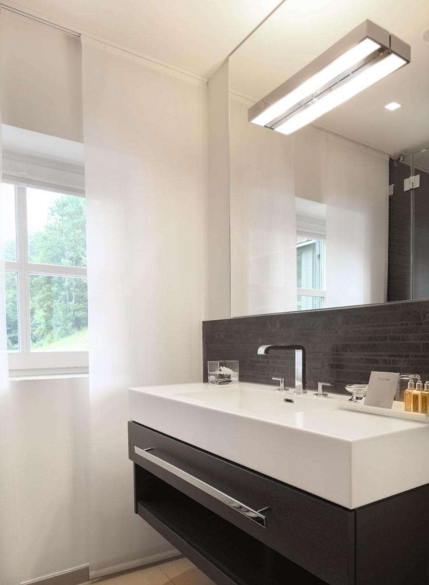 ein Badezimmer mit einem weißen Waschbecken und einem Spiegel in der Unterkunft Das Tegernsee in Tegernsee ein Badezimmer mit einem weißen Waschbecken und einem Spiegel in der Unterkunft Das Tegernsee in Tegernsee