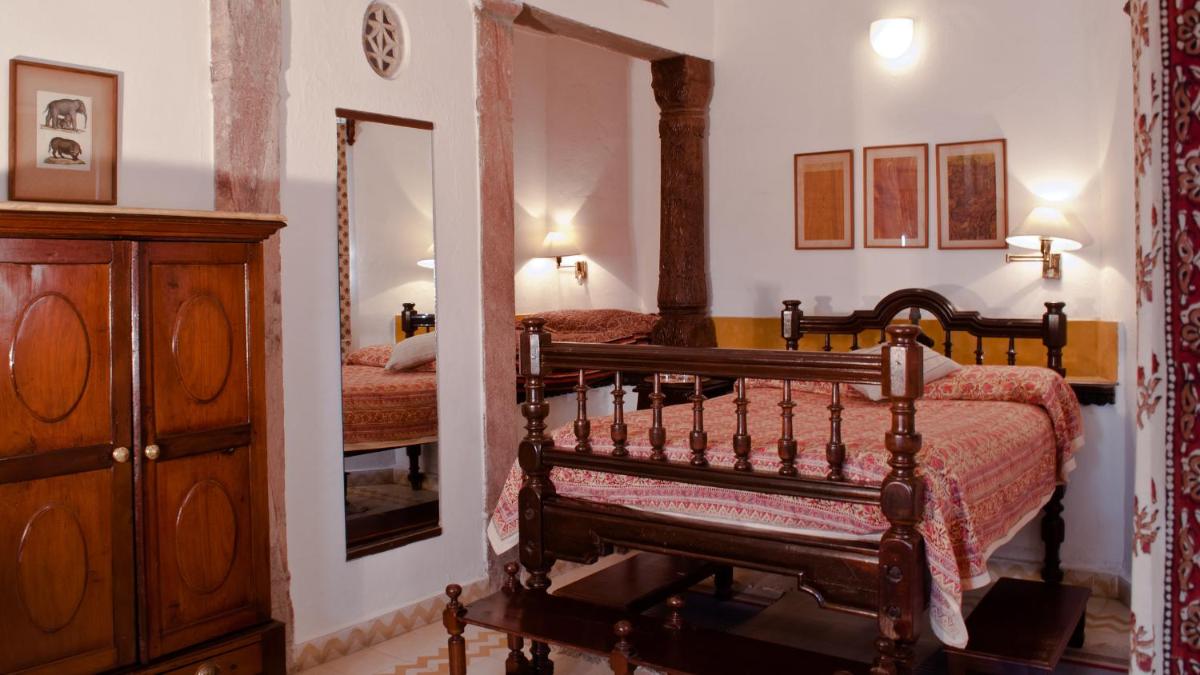 a bedroom with a bed and a dresser and a mirror at Neemrana Fort-Palace in Neemrana