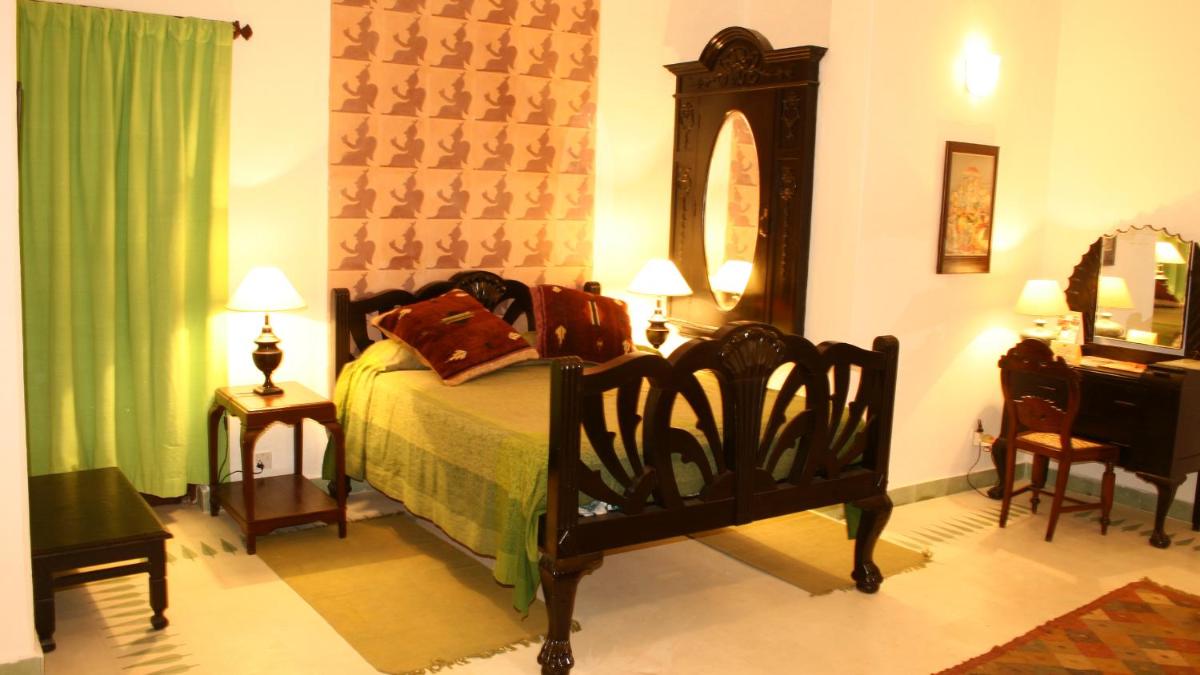 a bedroom with a bed and a mirror and a table at Neemrana Fort-Palace in Neemrana