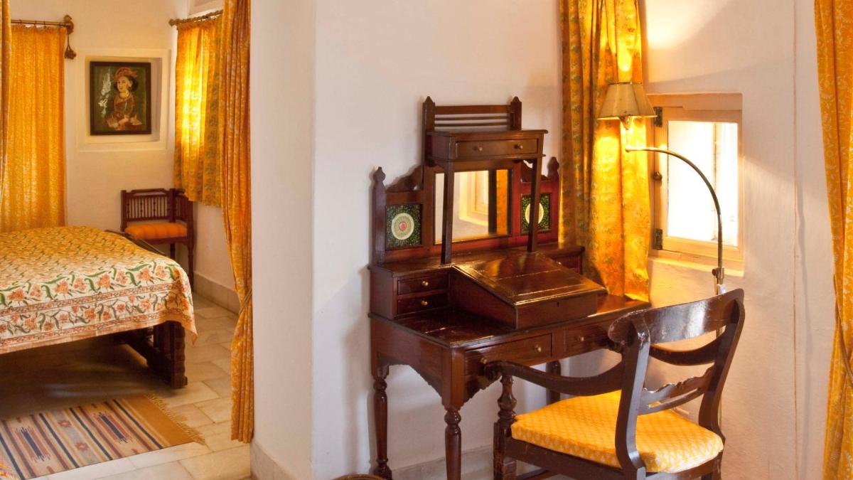 a desk with a mirror and a chair in a room at Neemrana Fort-Palace in Neemrana