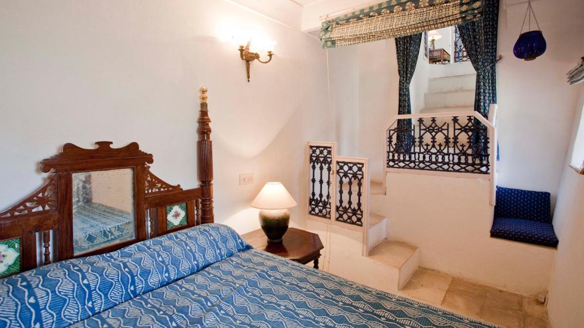 a bedroom with a bed with a blue comforter at Neemrana Fort-Palace in Neemrana