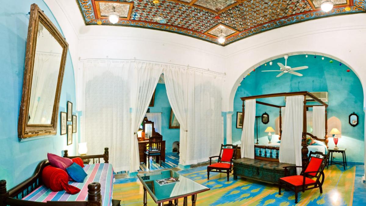 a room with a bedroom with a bed and chairs at Neemrana Fort-Palace in Neemrana