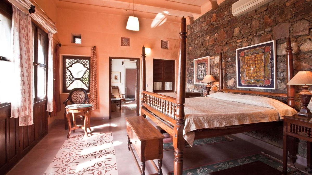 a bedroom with a bed and a stone wall at Neemrana Fort-Palace in Neemrana