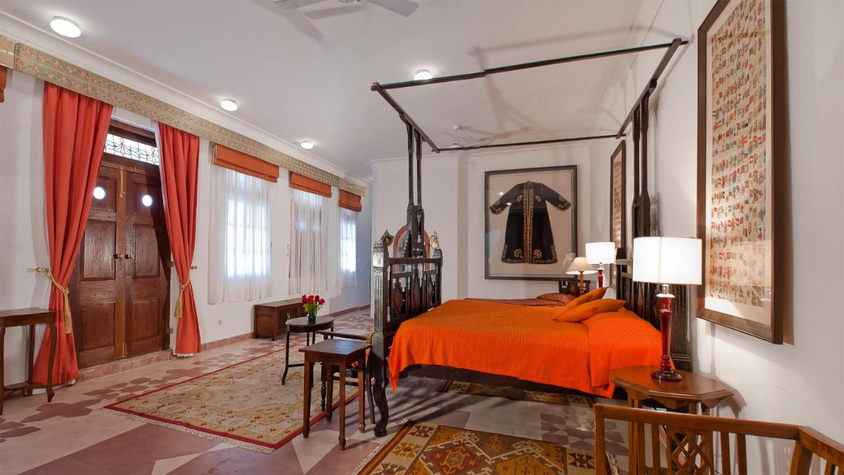 a bedroom with a bed with an orange bedspread at Neemrana Fort-Palace in Neemrana