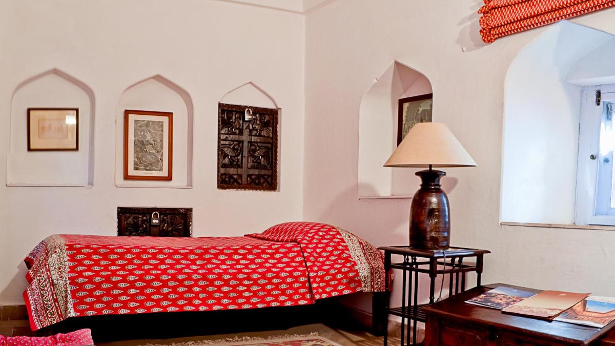 a bedroom with a bed and a table with a lamp at Neemrana Fort-Palace in Neemrana