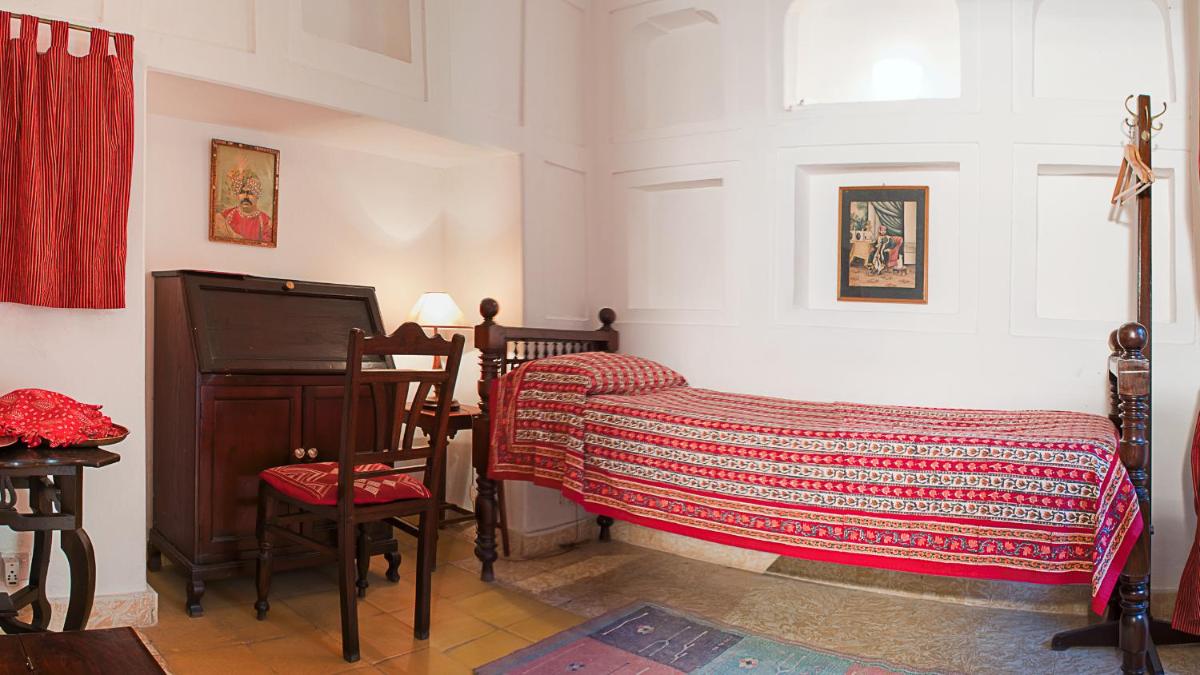 a room with a bed and a tv and a table at Neemrana Fort-Palace in Neemrana