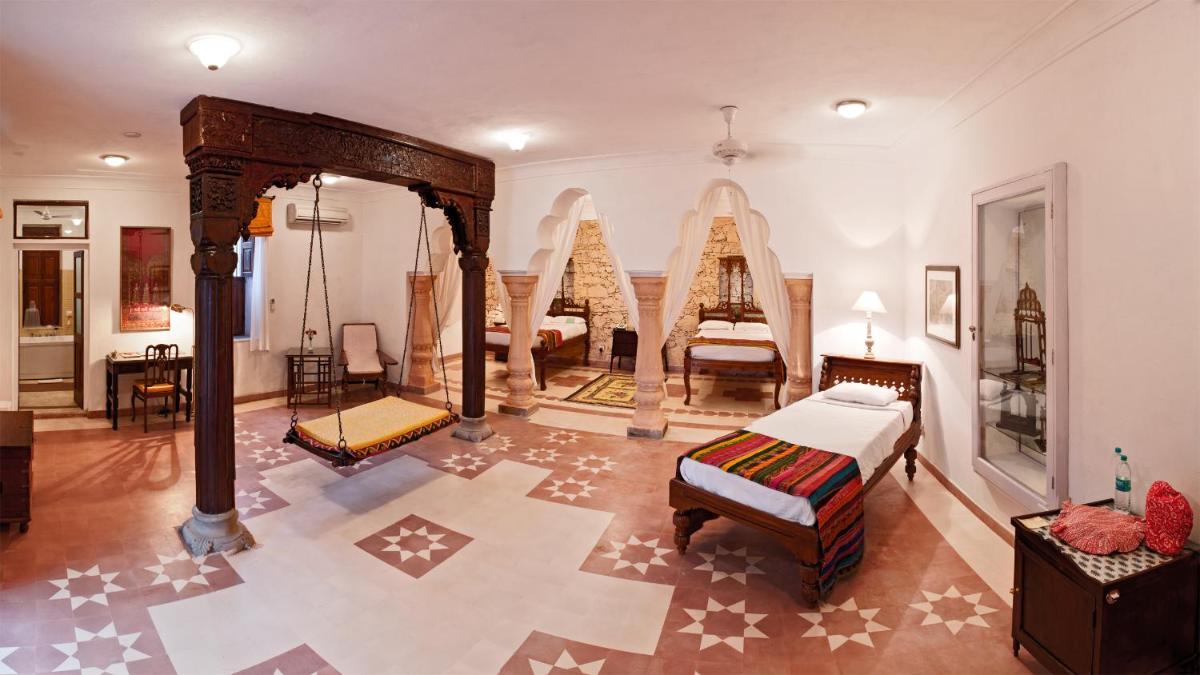 a room with a bedroom with a bed and a room with chairs at Neemrana Fort-Palace in Neemrana