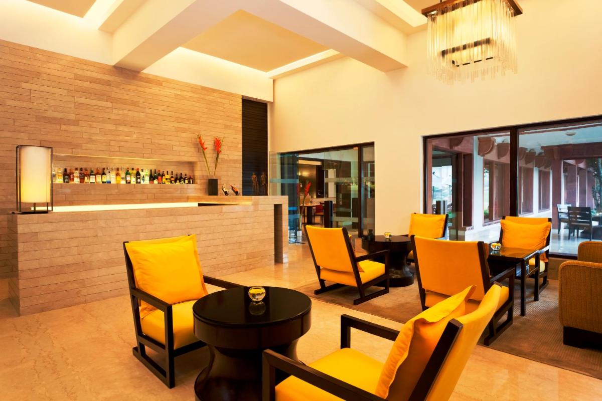a restaurant with yellow chairs and a bar at Trident Agra in Agra