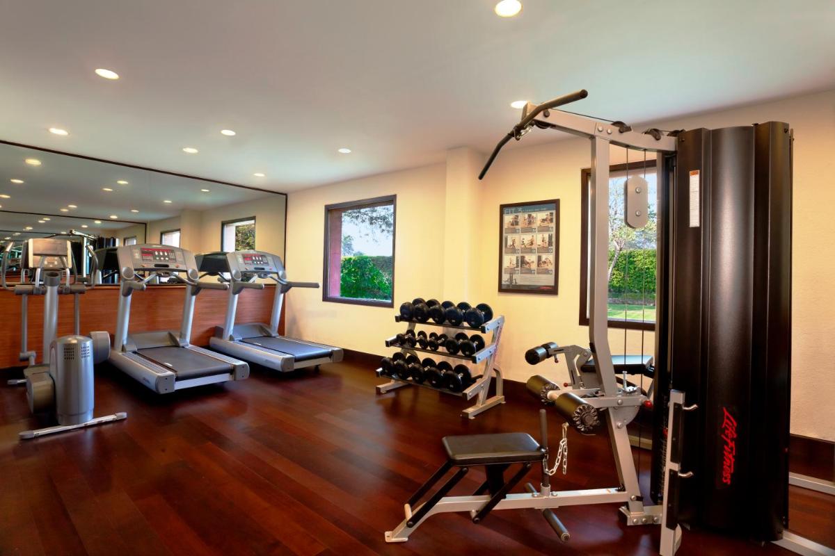 a gym with treadmills and weights in a room at Trident Agra in Agra