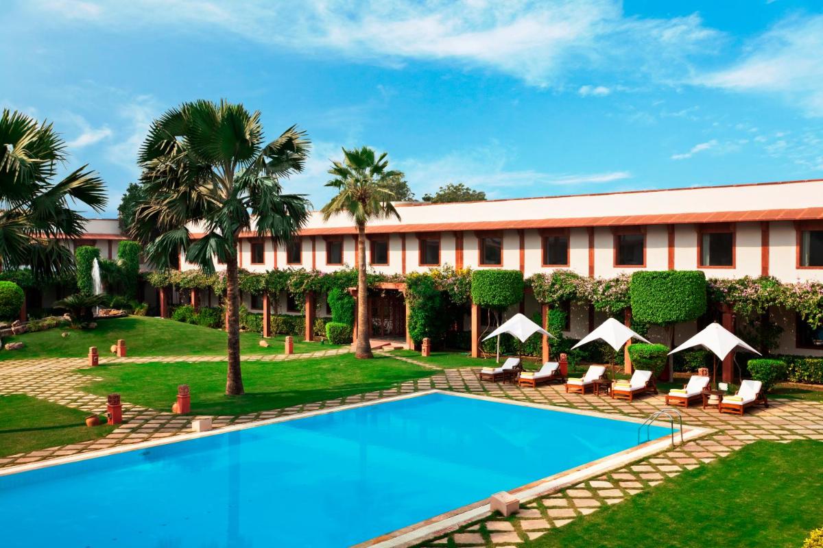 a resort with a swimming pool and palm trees at Trident Agra in Agra