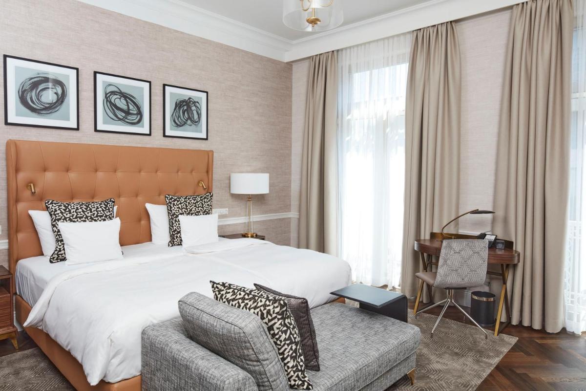 ein Schlafzimmer mit einem Bett, einem Stuhl und einem Schreibtisch in der Unterkunft Steigenberger Icon Parkhotel Düsseldorf in Düsseldorf