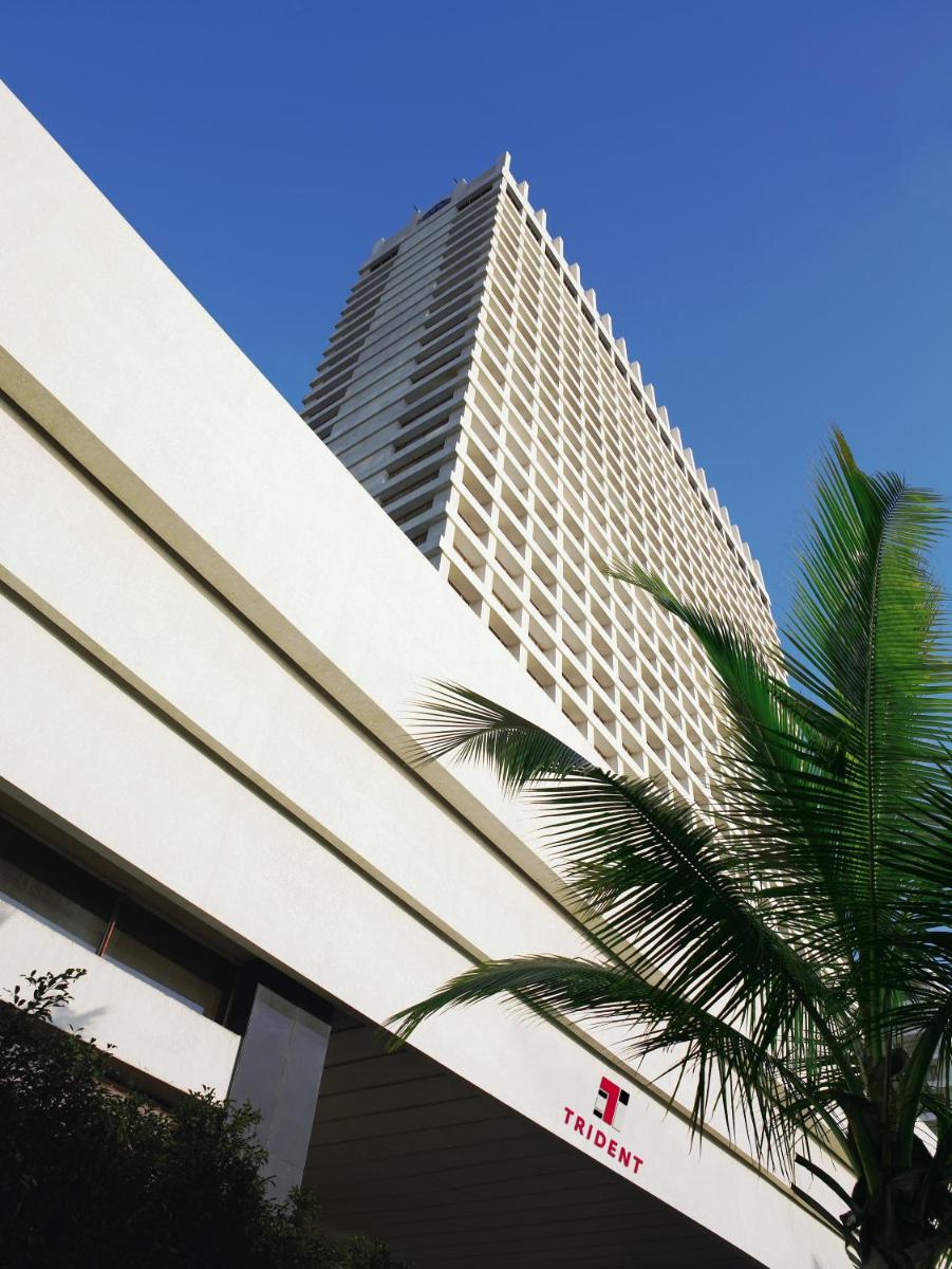 a tall building with a palm tree in front of it at Trident Nariman Point in Mumbai a tall building with a palm tree in front of it at Trident Nariman Point in Mumbai
