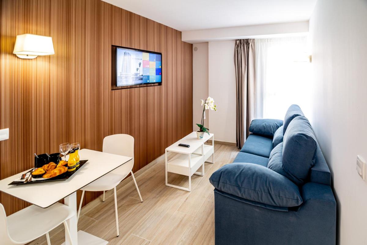 Una sala de estar con un sofá azul y una mesa. en Hotel Rosamar, en Benidorm