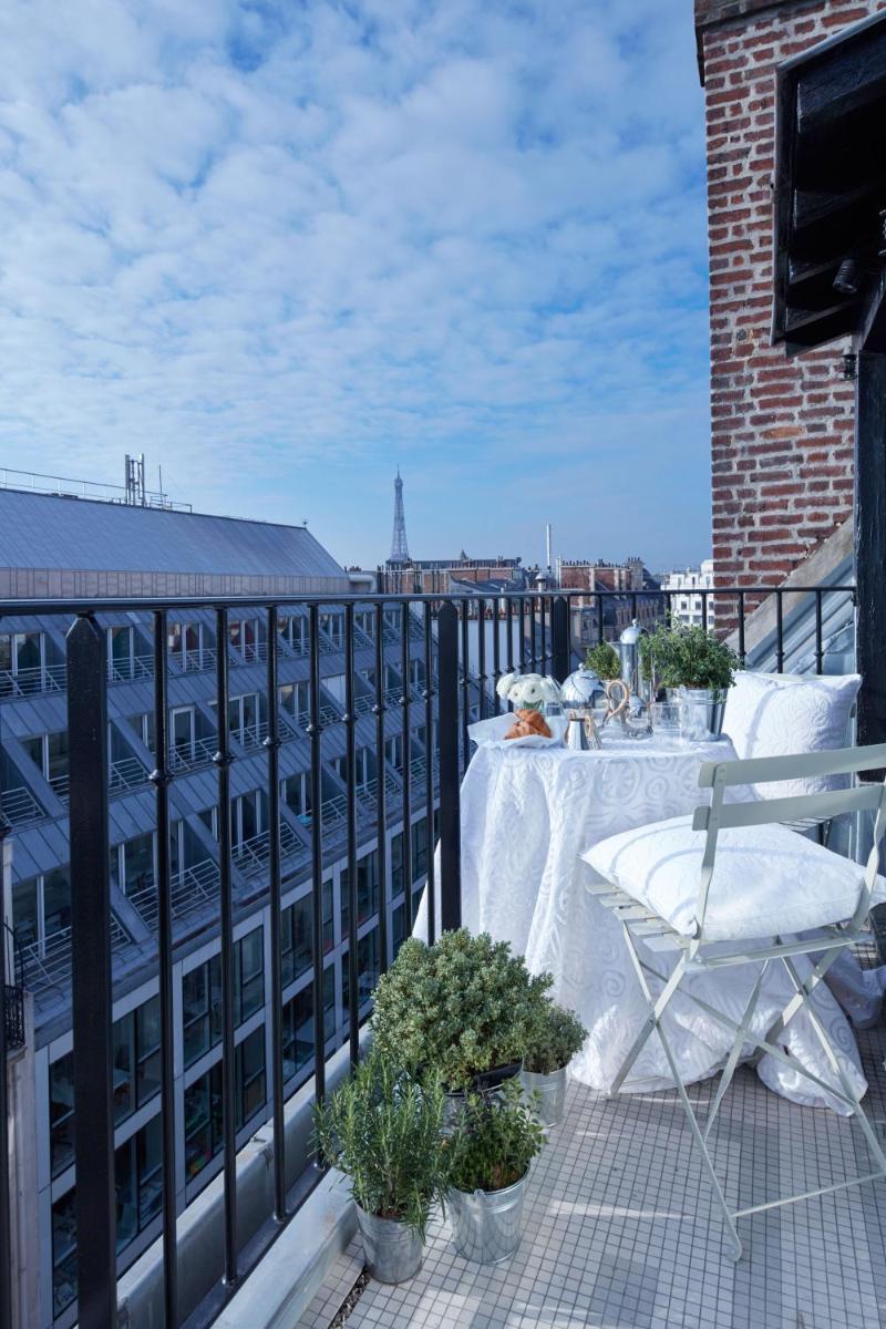 un balcon avec une table et une chaise sur un immeuble dans l'établissement Monsieur George Hotel & Spa - Champs-Elysées, à Paris