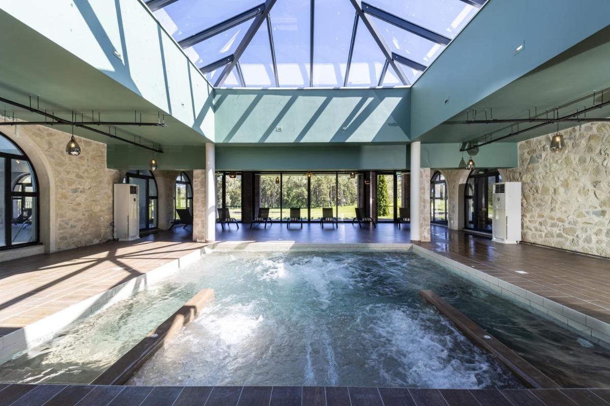 une piscine intérieure avec un plafond en verre dans l'établissement Château et Golf De Taulane, à La Martre