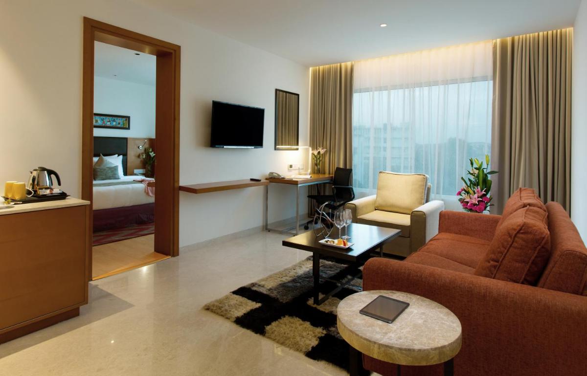 a living room with a couch and a room with a bed at Mercure Hyderabad KCP Banjara Hills, An Accor Hotel in Hyderabad a living room with a couch and a room with a bed at Mercure Hyderabad KCP Banjara Hills, An Accor Hotel in Hyderabad