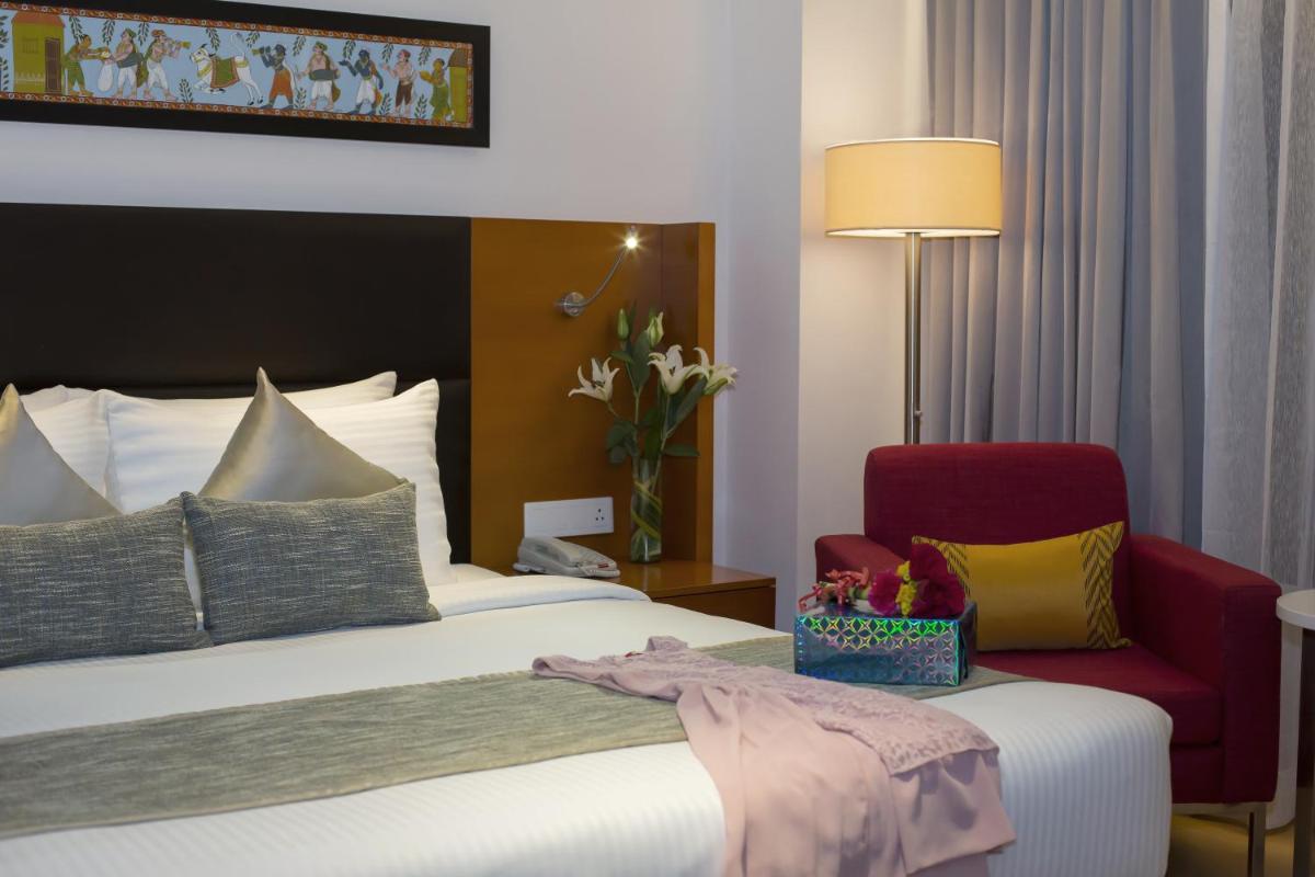 a hotel room with a bed and a red chair at Mercure Hyderabad KCP Banjara Hills, An Accor Hotel in Hyderabad