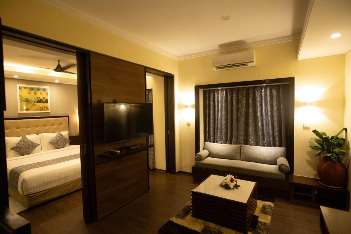 a hotel room with a bed and a couch at Deltin Suites in Candolim