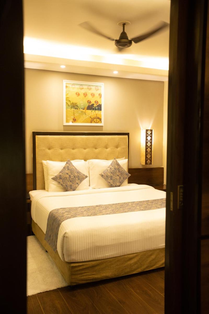 a bedroom with a large bed and a ceiling at Deltin Suites in Candolim