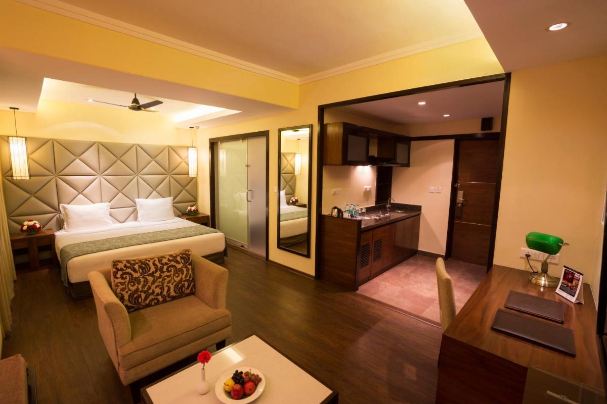 a hotel room with a bed and a living room at Deltin Suites in Candolim