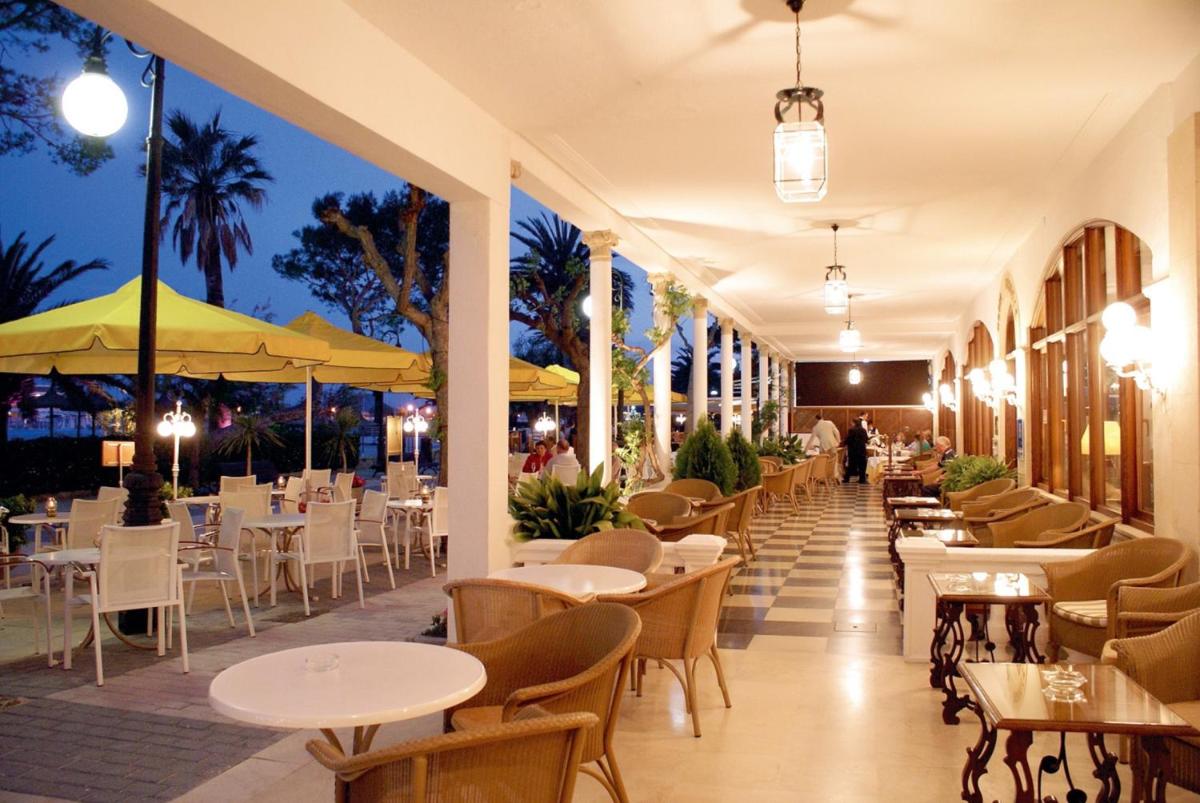 Un restaurante con mesas y sillas blancas y mesas y sillas. en Hotel Miramar Mallorca, en Puerto Pollensa