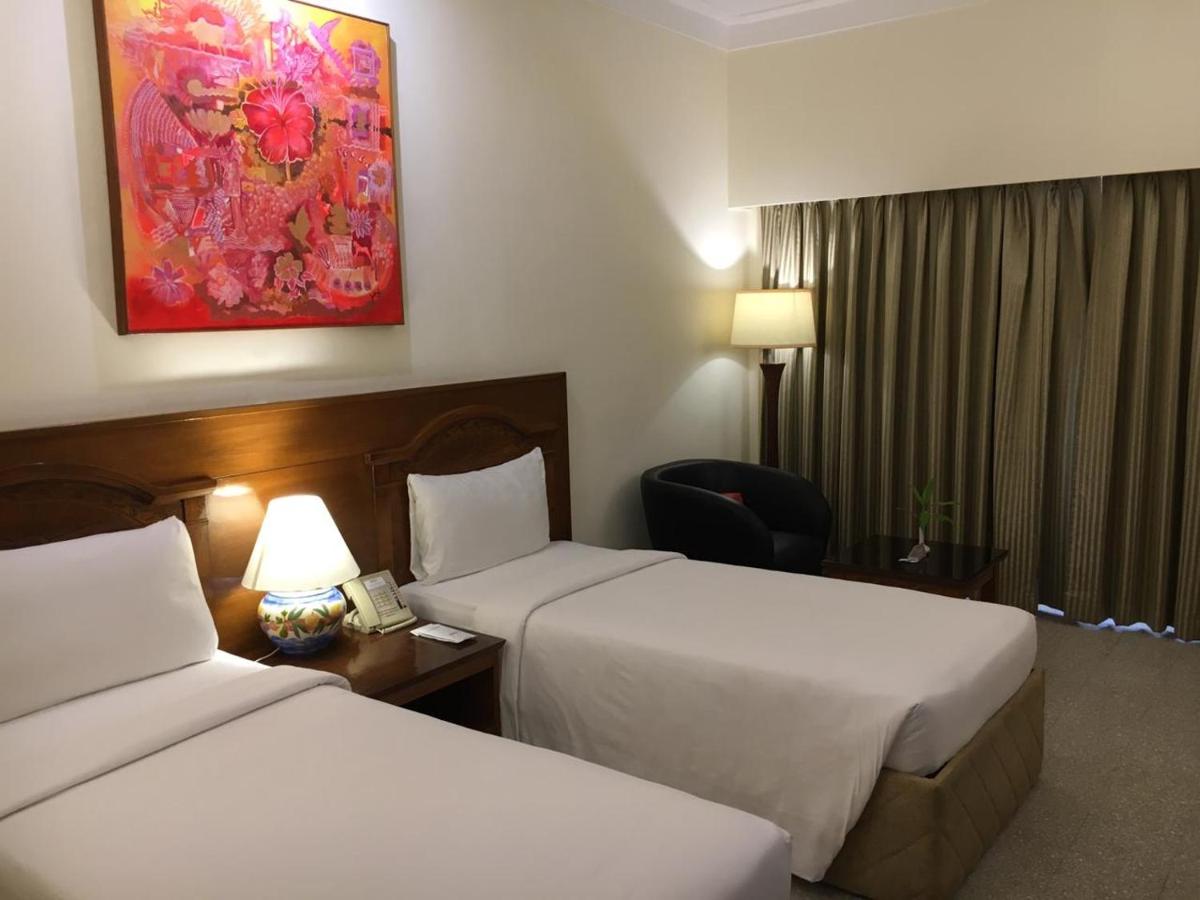 a hotel room with two beds and a chair at Radisson Goa Candolim in Candolim