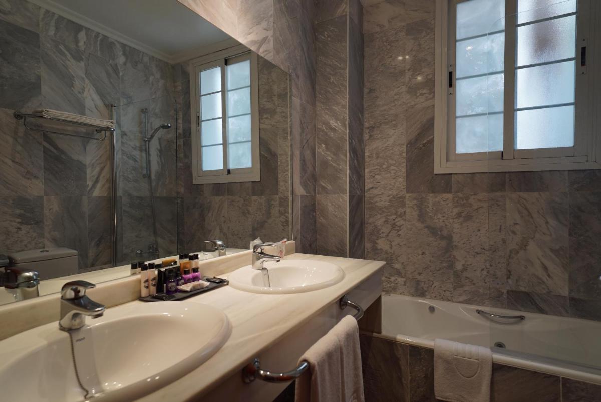 Un baño con lavabo, bañera y espejo. en Hotel Artmadams, en Palma de Mallorca