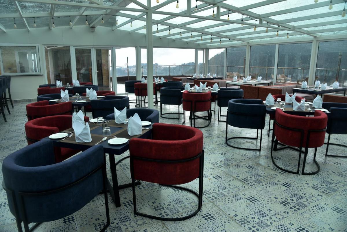 a dining room with tables and chairs and windows at The Orchid Shimla in Shimla