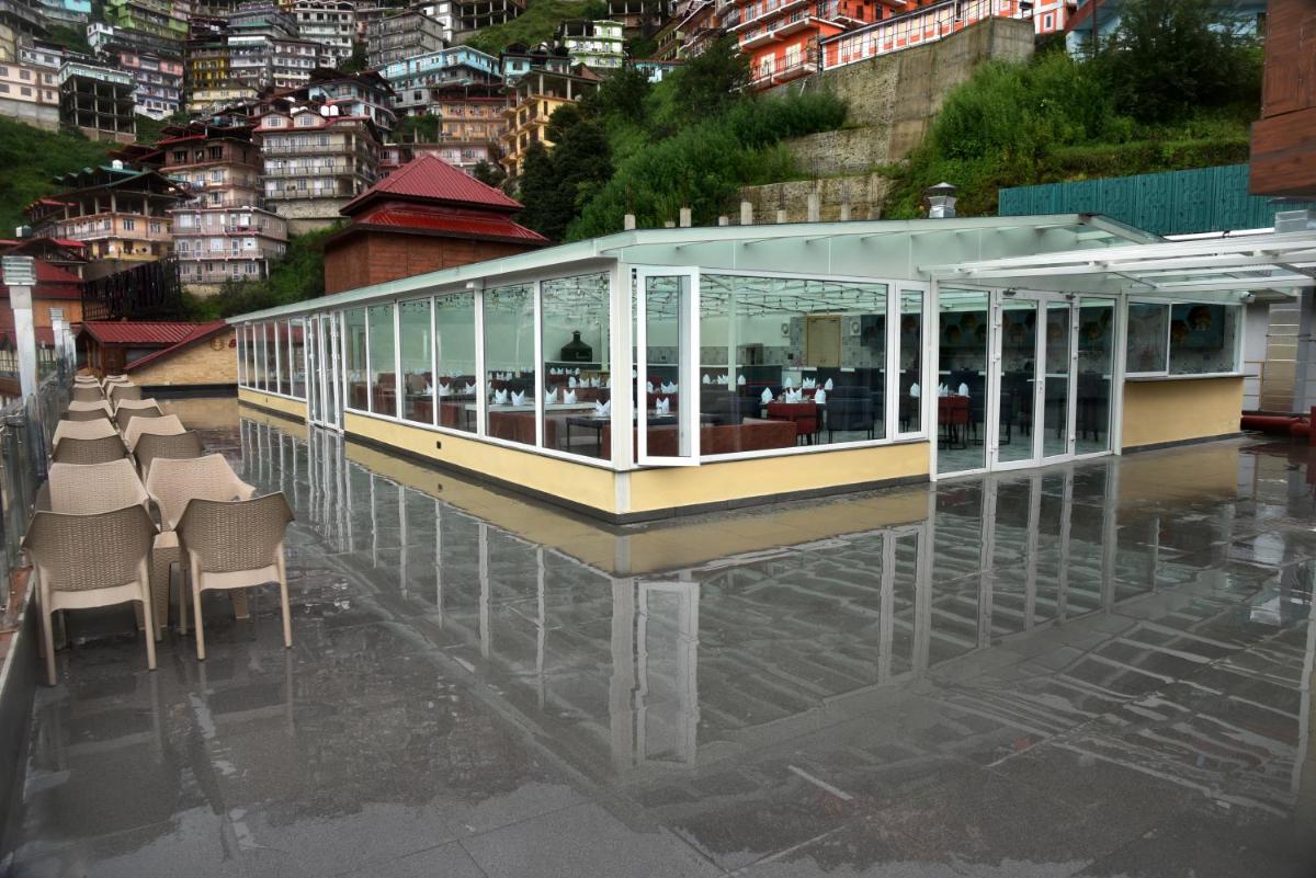 a restaurant with tables and chairs on the water at The Orchid Shimla in Shimla