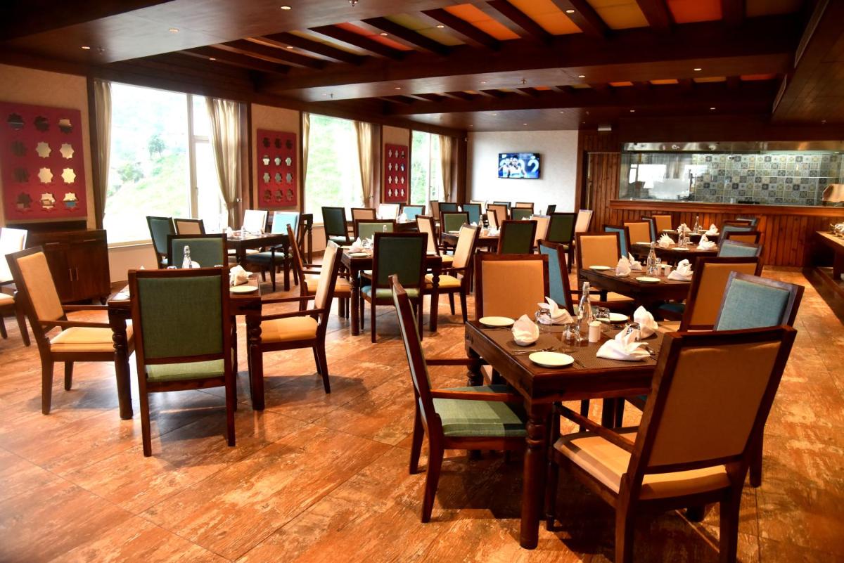 a dining room with tables and chairs in a restaurant at The Orchid Shimla in Shimla