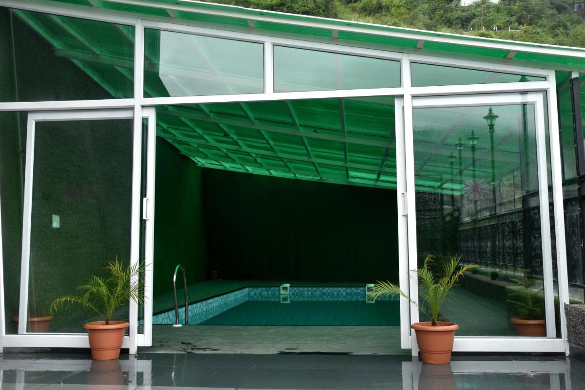a large glass building with a swimming pool inside at The Orchid Shimla in Shimla