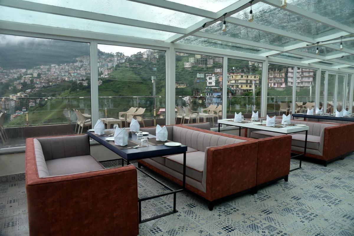 a restaurant with couches and tables and windows at The Orchid Shimla in Shimla