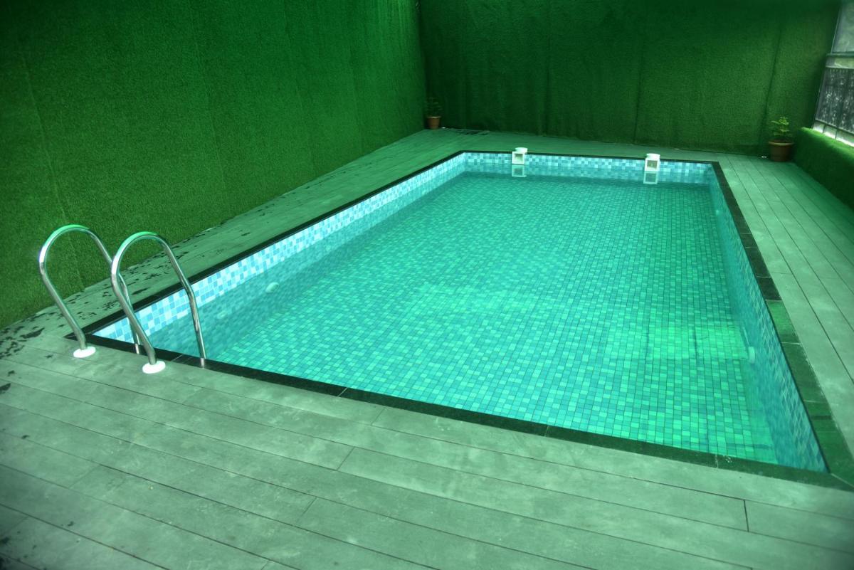 a swimming pool in a room with a green wall at The Orchid Shimla in Shimla