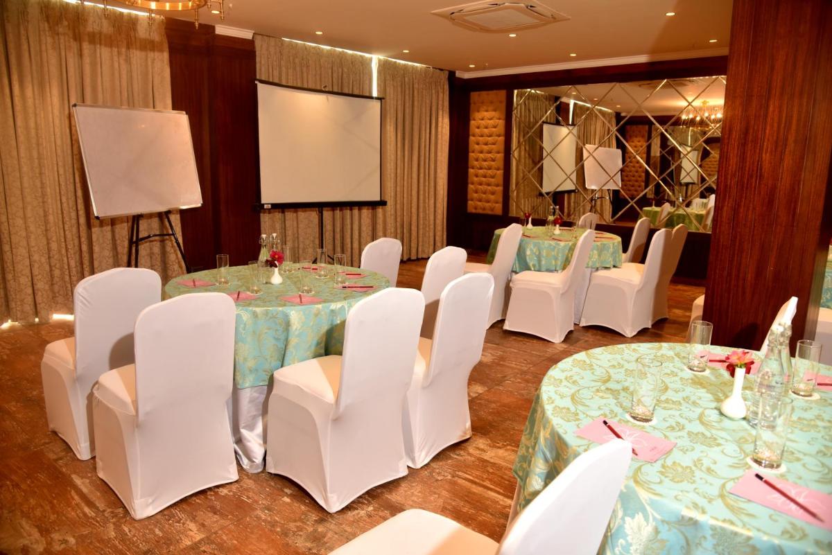 a conference room with white chairs and tables and a screen at The Orchid Shimla in Shimla