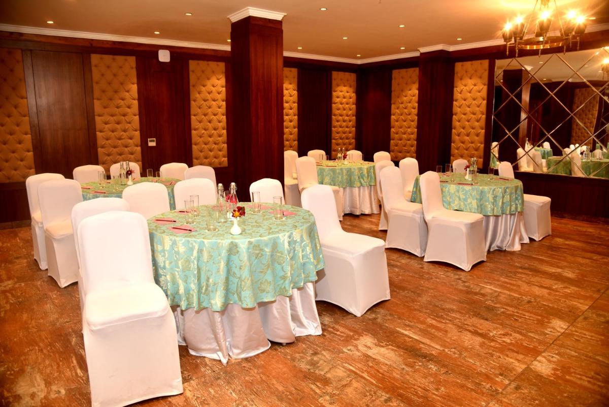 a banquet hall with tables and white chairs at The Orchid Shimla in Shimla